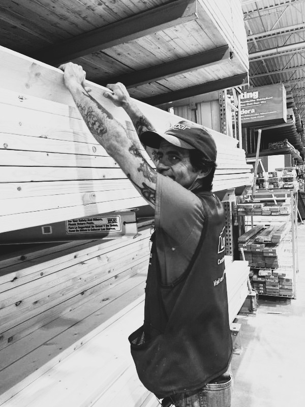 picture of guest Sonny pulling down lumber off shelf while working at Lowe's
